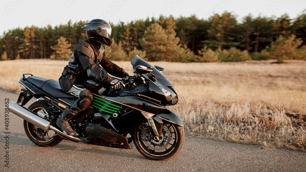 Obraz premium Motorcyclist rides along a forest road. Have fun on an empty road on a sports motorcycle. Copy space for your customized text