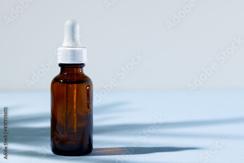 Glass jar with skincare liquid on gray background with shadow