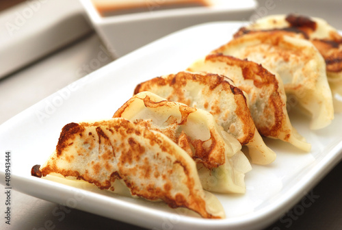 Japanese dumplings or Gyoza in white plate with gyoza sauce on a wooden table in a restaurant. Selective focus