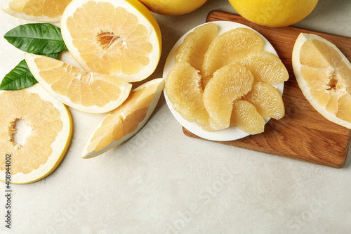 Ripe pomelo and plate with pomelo slices on white textured background photo