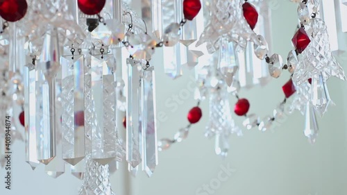 Close up of Vintage Chandlier with Shiny White and Red Gem Beads, Refracting Sun Light with Colorful Flares in Living Room photo