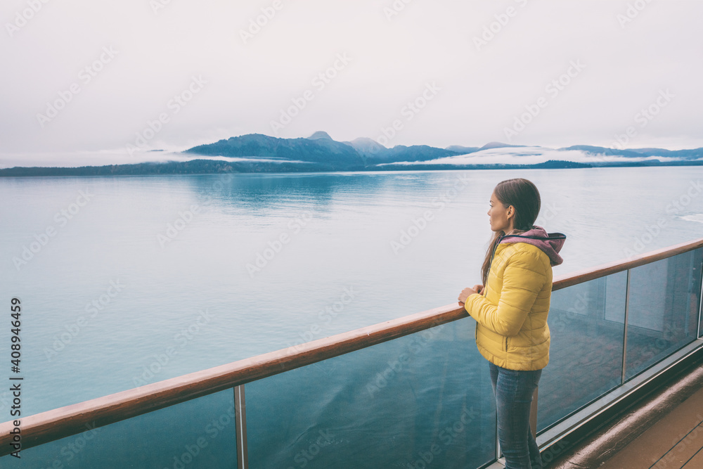 Fototapeta premium Alaska cruise travel tourist looking at mountains landscape from balcony deck of ship. Inside passage Glacier bay scenic vacation travel woman enjoying scenery from boat.