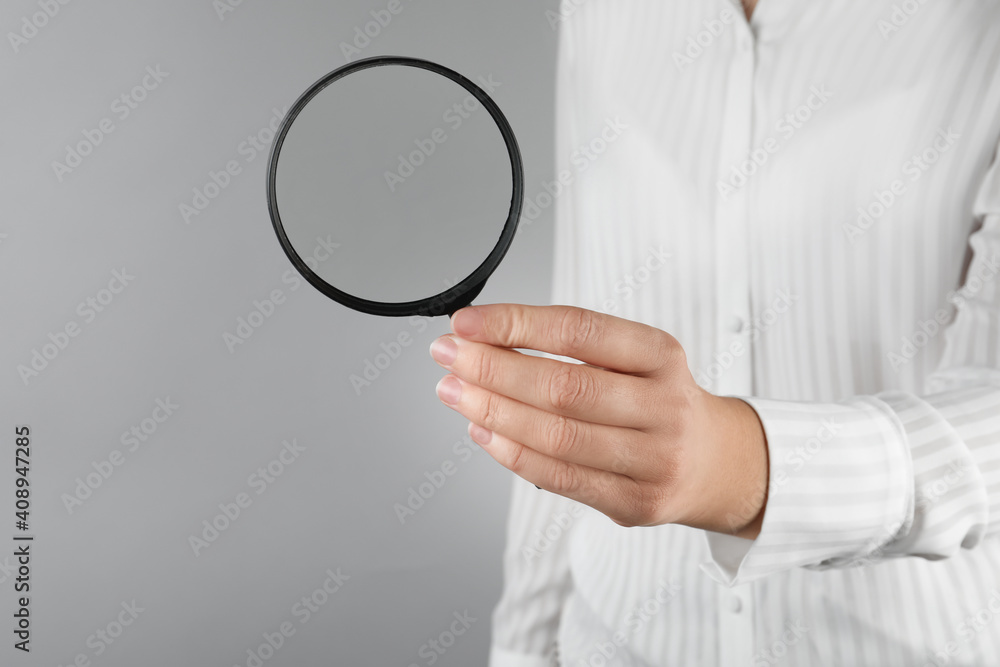 Woman holding magnifying glass on grey background, closeup. Find keywords concept Woman holding magnifying glass on grey background, closeup. Find keywords concept