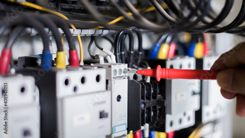 Electrician engineer work tester measuring voltage and current of power electric line in electical cabinet control.  © bancha