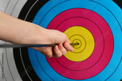Woman pulling out arrow from archery target, closeup