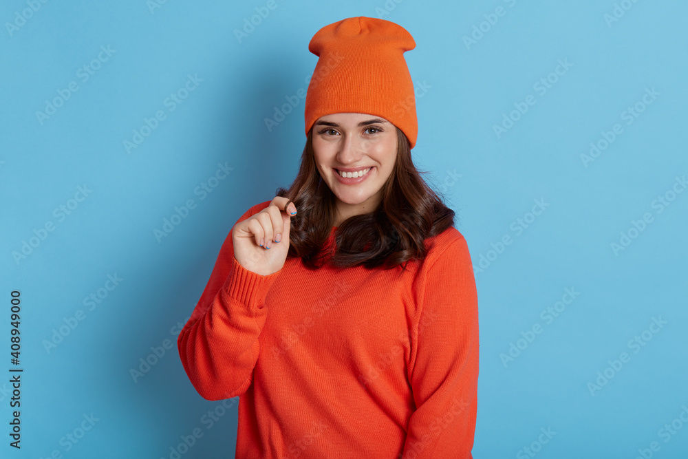 European woman looking playful at camera and touching her hair, wearing casual clothing and cap, has flirting facial expression, feels positive emotions, being satisfied. European woman looking playful at camera and touching her hair, wearing casual clothing and cap, has flirting facial expression, feels positive emotions, being satisfied.