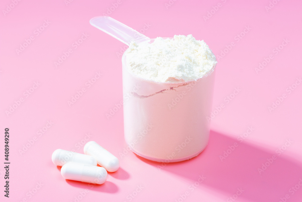 Protein scoop and capsules on pink background close-up Protein scoop and capsules on pink background close-up