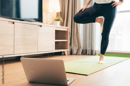 Home workout during Covid 19 pandemic lockdown. A healthy Asian woman in asana Surya Namaskar posture, she follow the step from online yoga programs in the website. Happy self isolation, New normal.