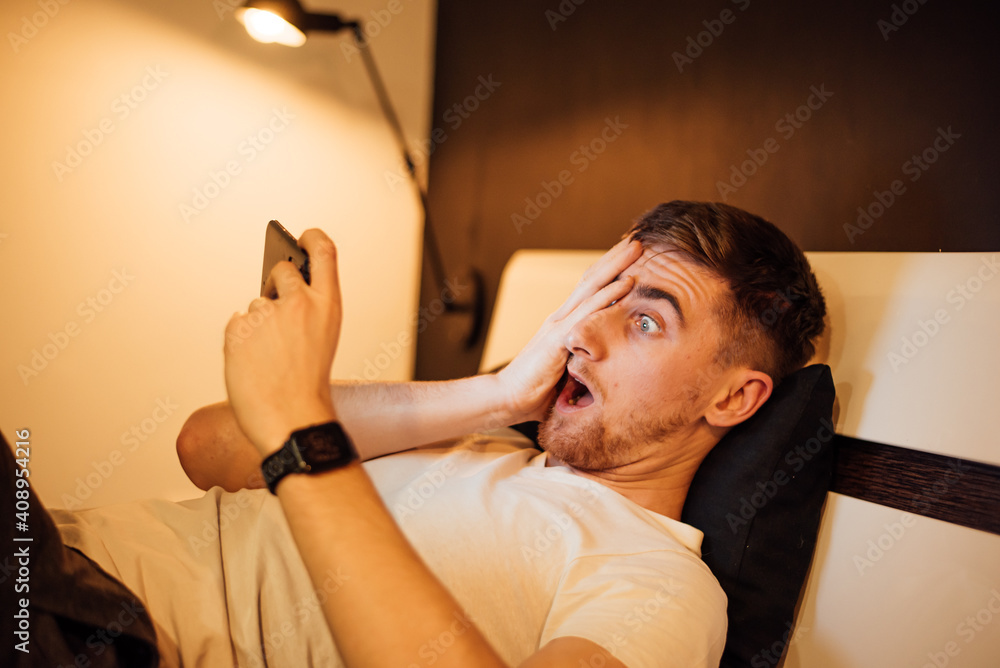 The guy emotionally looks at the phone. Anger and surprise lost money in an online casino The guy emotionally looks at the phone. Anger and surprise lost money in an online casino