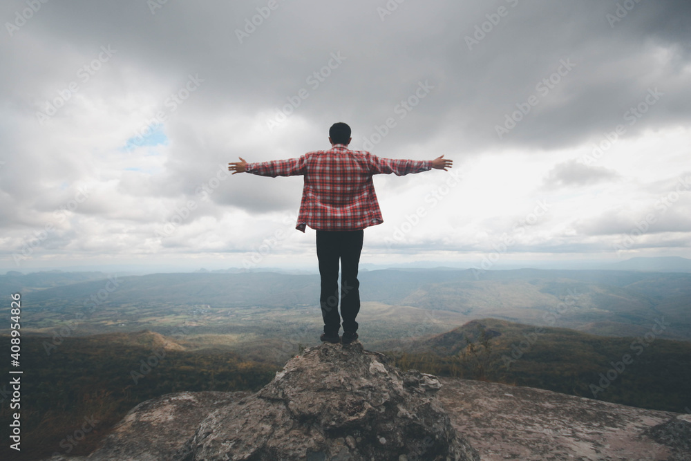 Obraz premium A man stand on the top mountain cliff and acting of freedom life style travel trip successful background textures concept.
