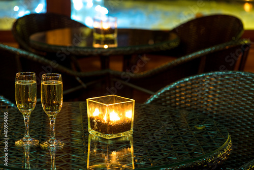 Two glass with champagne and burning candle on table