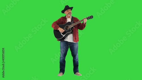 Man in cowboy hat playing on guitar and singing on a Green Screen, Chroma Key. photo