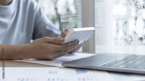 Financial or accounting professionals use a laptop to analyze the company's revenue-expenses graph to prepare for presentation to the chief executive and partner, businesswomen working in the room.