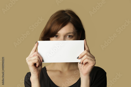 Portrait of young woman holds blank white paper tag.
