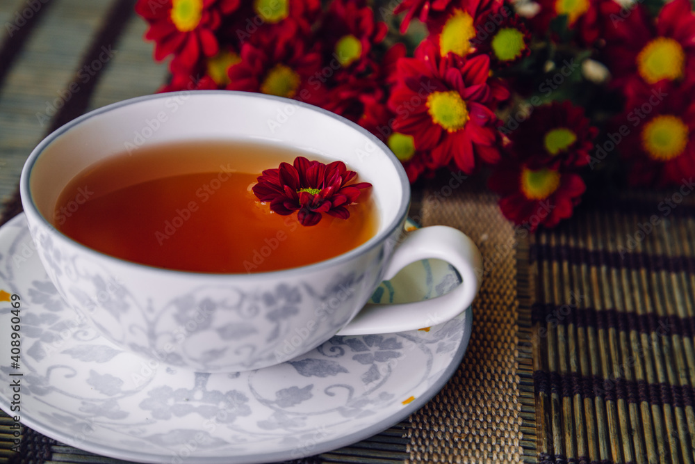 Cup of tea. Focus on the flower in the cup, with a blurred background.