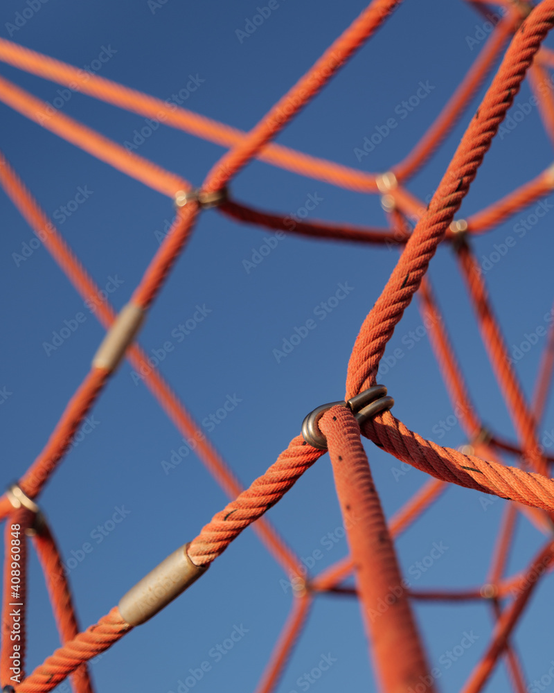 Abstract detail picture of climbing frame with red ropes and blue sky in playground Abstract detail picture of climbing frame with red ropes and blue sky in playground