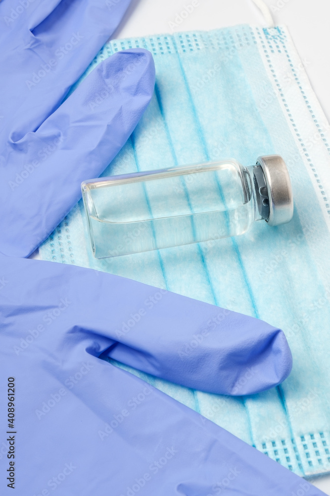 Vaccine on a medical mask and blue gloves on a light background. Concept of coronavirus quarantine. Vaccine on a medical mask and blue gloves on a light background. Concept of coronavirus quarantine.