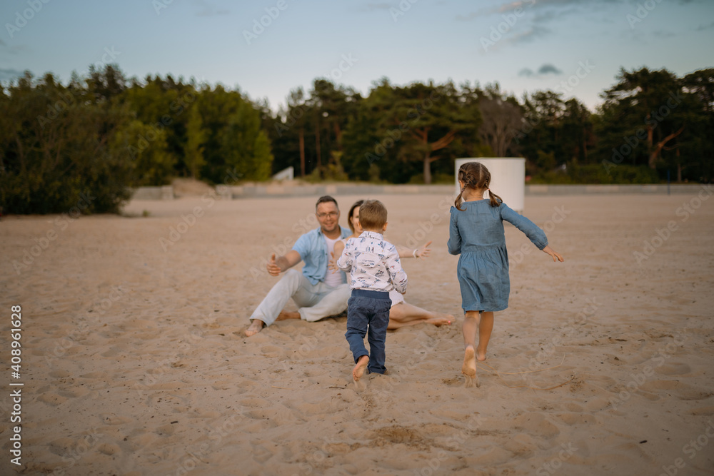 happy kids running towards their parents on beach in summer. Family time concept. Image with selective focus