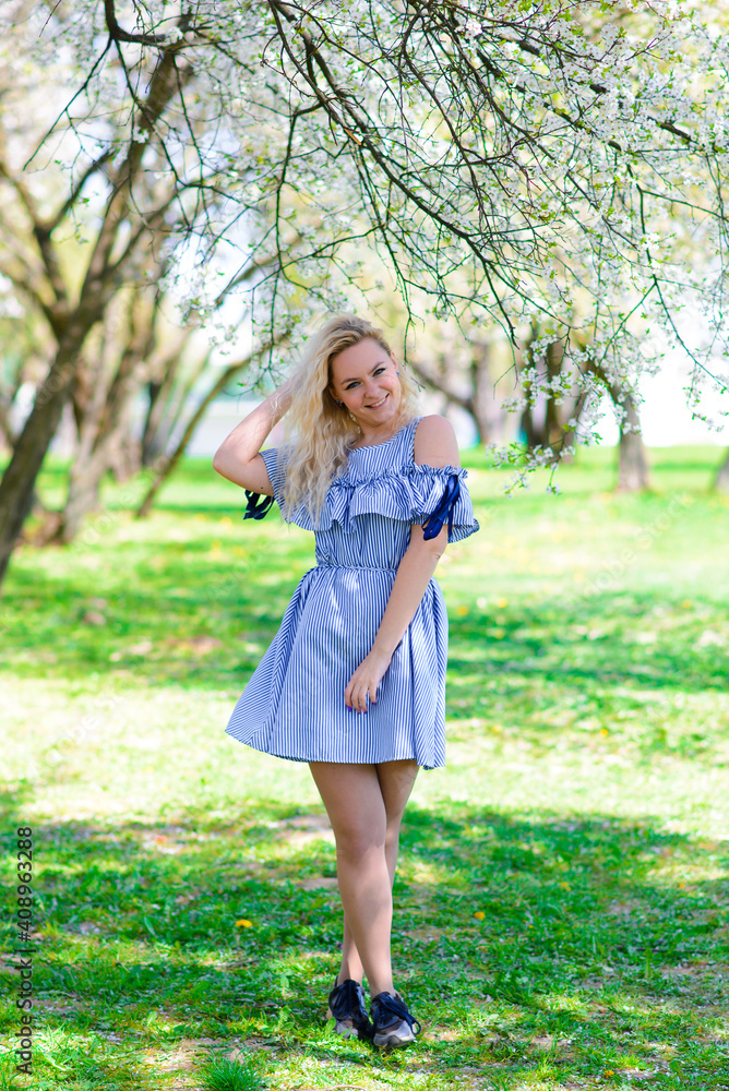 Woman with gorgeous smile having fun in blooming garden. Female in blue dress on natural background. Woman with gorgeous smile having fun in blooming garden. Female in blue dress on natural background.