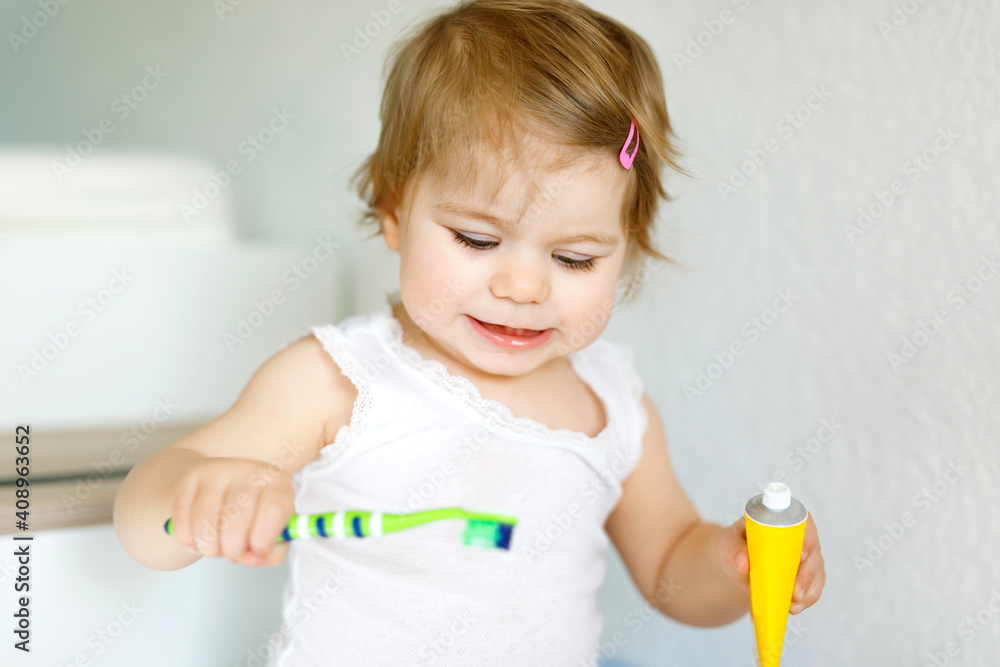 Little baby girl holding toothbrush and brushing first teeth. Toddler learning to clean milk tooth. Little baby girl holding toothbrush and brushing first teeth. Toddler learning to clean milk tooth.