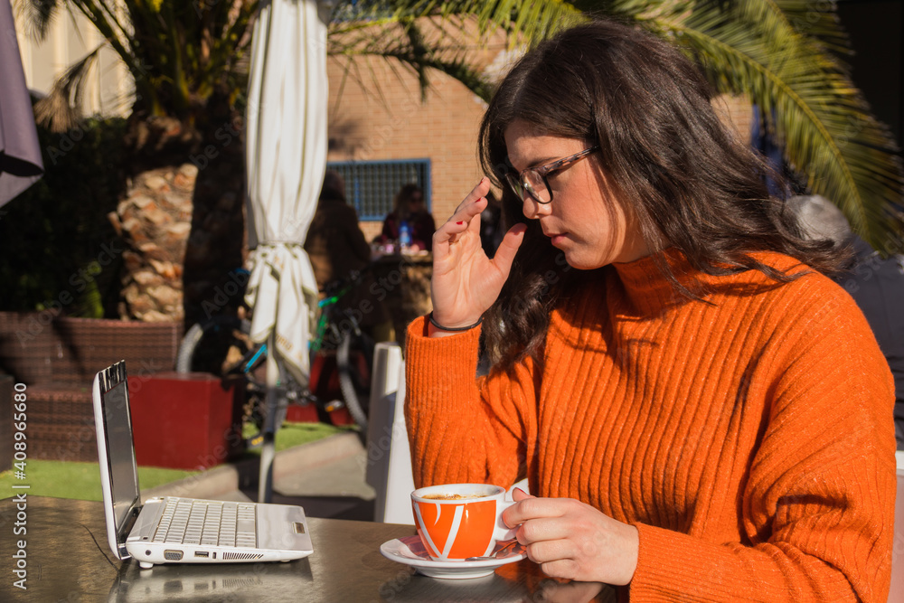 Woman, taking off her glasses and consulting her laptop computer in a coffee shop. Woman, taking off her glasses and consulting her laptop computer in a coffee shop.