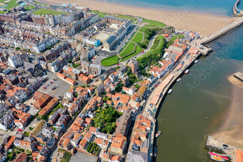 Aerial photo of the beautiful town of Whitby in the UK, North Yorkshire in the UK showing a top down view of the village by the harbour and sandy beach on a hot sunny summers day