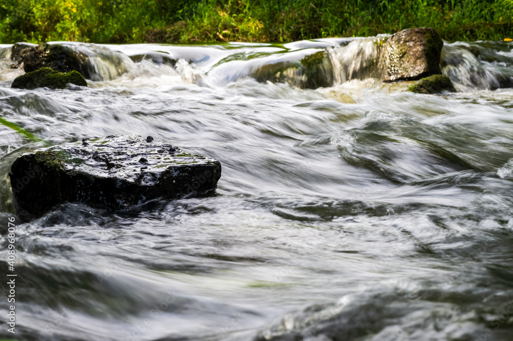 River flow over rocks in summer day. Waves of the river flow. Relaxing nature landscape scenics