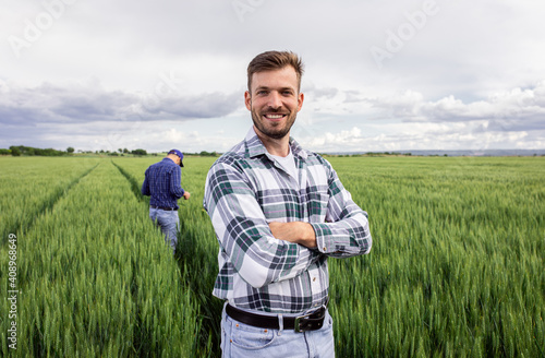 Fotografia Portrait of farmer standing in green wheat field with his colleague in background