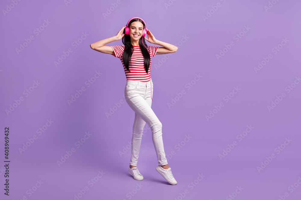 Full body photo of cool positive lady hipster listen stereo music song touch hands headphones isolated on violet color background Full body photo of cool positive lady hipster listen stereo music song touch hands headphones isolated on violet color background