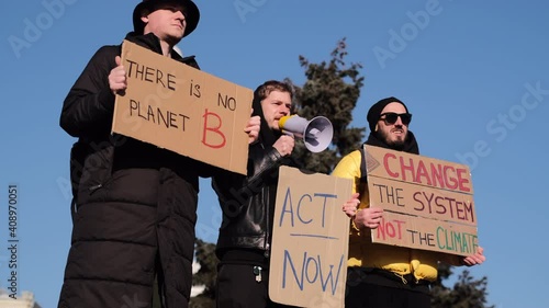 A group of people with banners and a megaphone in hand are protesting in the city square for svae planet clean world act now     photo