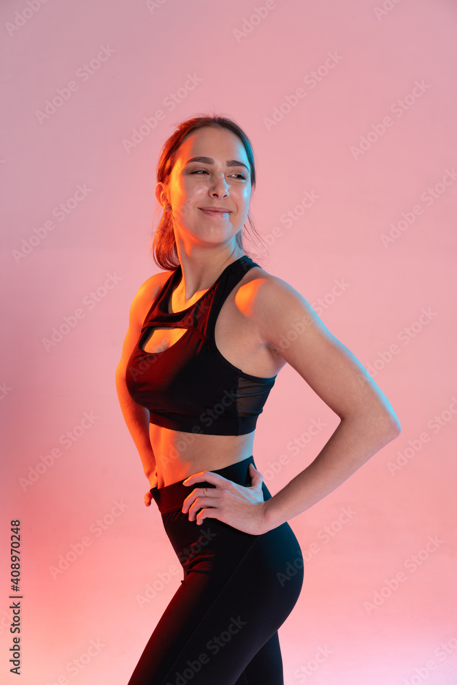 Obraz premium Sportive young woman holds her hands waist and poses with satisfied face.