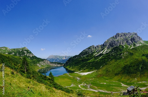 gorgeous green mountain landscape with a deep blue lake panorama © thomaseder