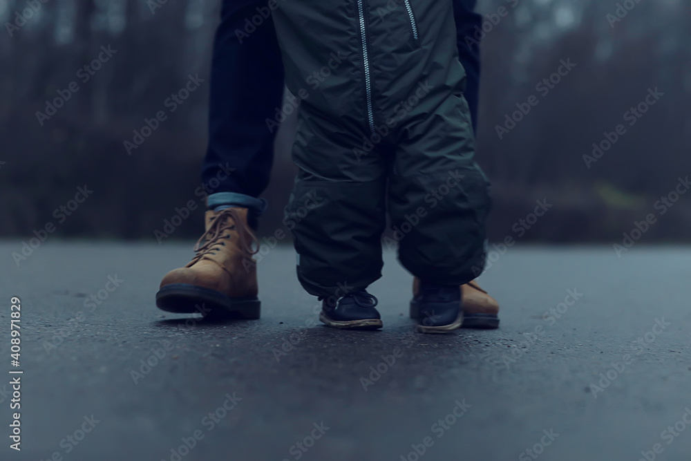 first step kid learns to walk, walk child and father in autumn in the park, winter style november first step kid learns to walk, walk child and father in autumn in the park, winter style november