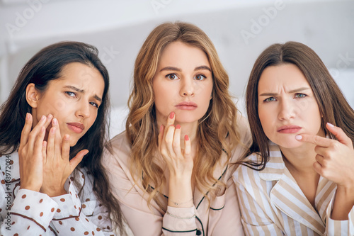 Three girls touching their skin looking unsatisfied