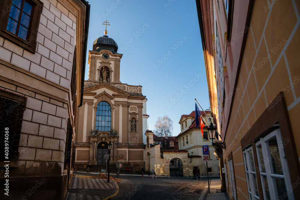 Old beautiful church of St John of Nepomuk near Prague Castle, clock tower, baroque stucco, Hradcany district in sunny winter day, Prague, Czech Republic