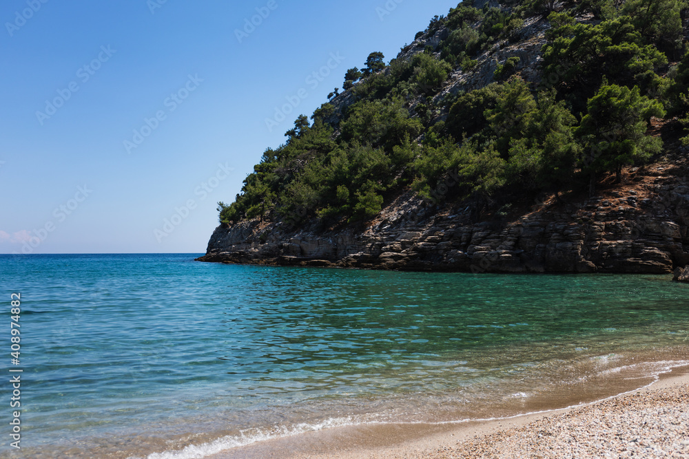 summer seascape on the island, a golden sand beach, green hills, mountains and rocks, blue and turquoise sea and clear sky