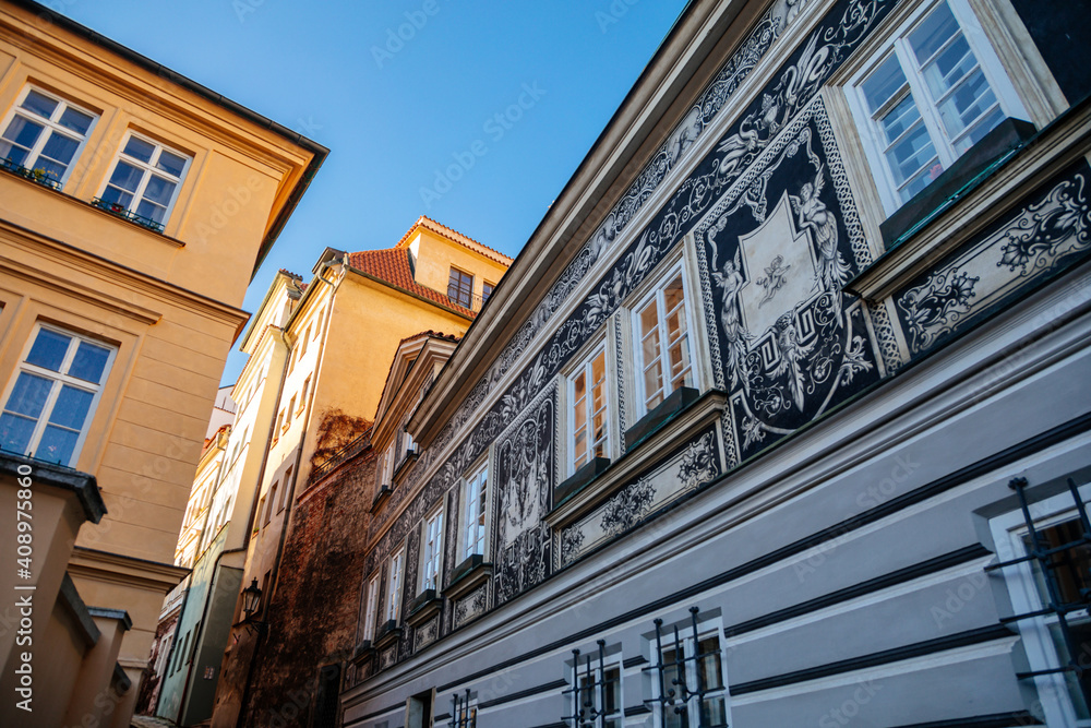 Fototapeta premium Fascinating narrow picturesque street Jansky vrsek with baroque and renaissance historical house richly decorated with sgraffito, sunny day at Lesser Town, Prague, Czech Republic