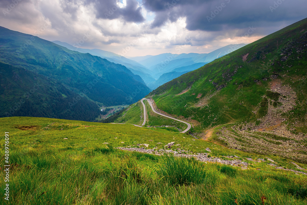 road in high mountains of romania. popular travel destination of fagaras ridge. route 7c is also known as transfagarasan. dramatyc summer weather with clouds on the sky