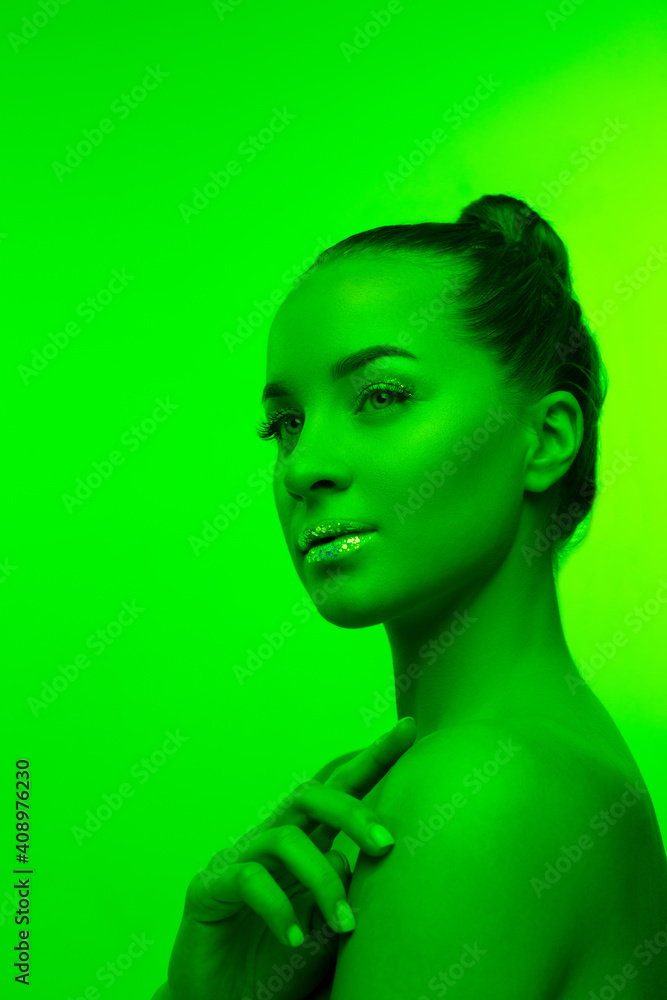 Inspired. Handsome woman's portrait isolated on green studio background in neon light, monochrome. Beautiful female model. Concept of human emotions, facial expression, sales, ad, fashion and beauty.