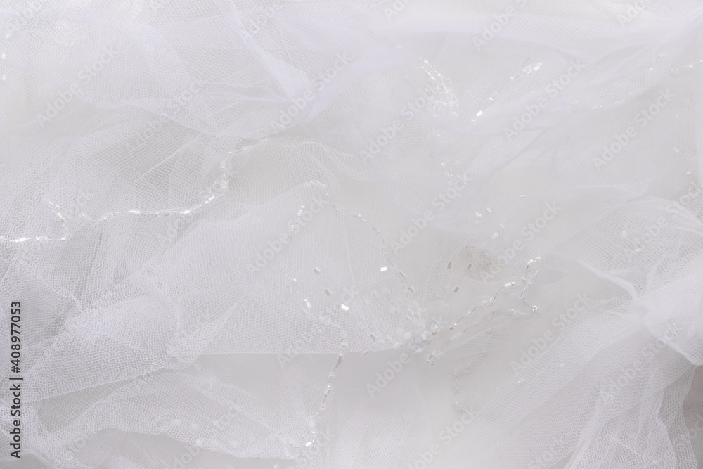 Delicate white tulle background. Blurred wedding veil with beads closeup. Selective focus