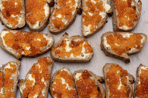 Sliced black bread with butter and red caviar is on the table.