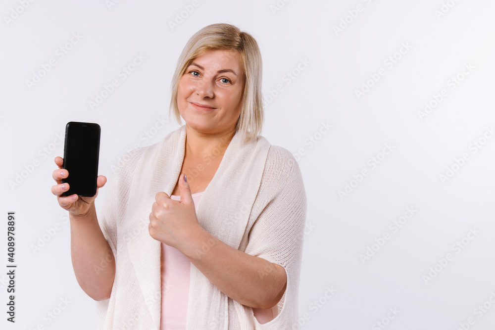 Senior woman holding smartphone in hands showing class at camera. White background and empty side space. Senior woman holding smartphone in hands showing class at camera. White background and empty side space.