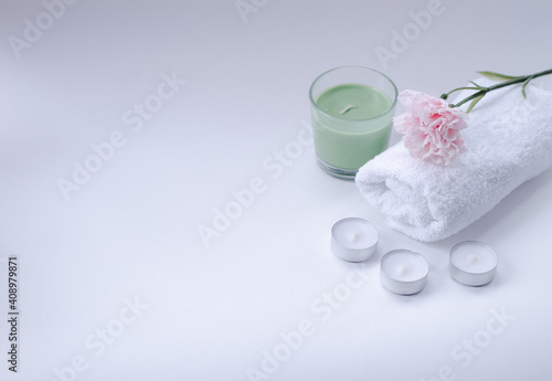 white, terry towel with a pink flower on top and candles on a white background