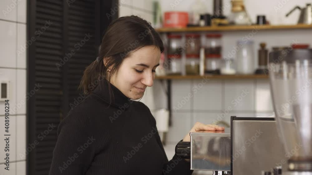 the girl turns on the coffee machine and looks shyly into the camera the girl turns on the coffee machine and looks shyly into the camera