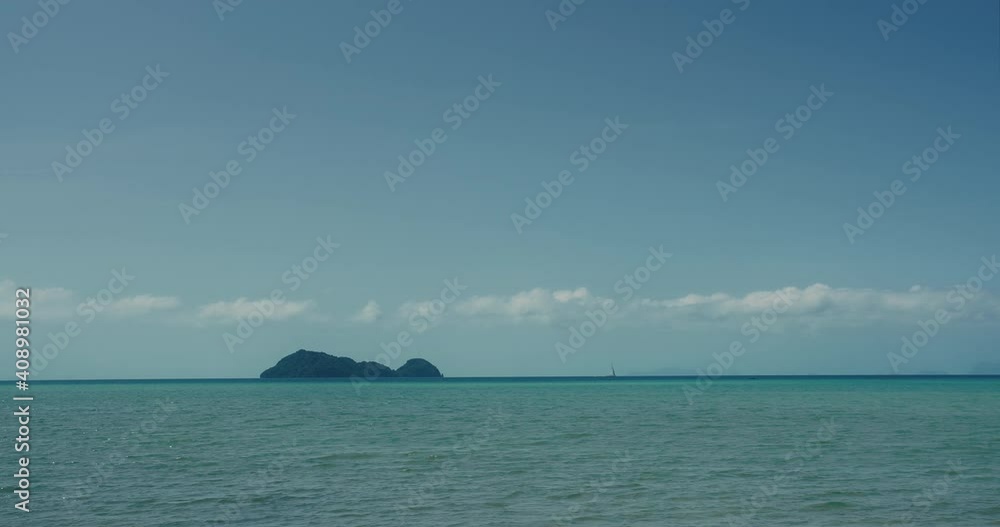 Blue lagoon sea view in midday with island and sailboat on horizon Blue lagoon sea view in midday with island and sailboat on horizon