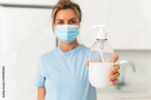 Woman using hand sanitizer or liquid soap for hands disinfection at home © blackday
