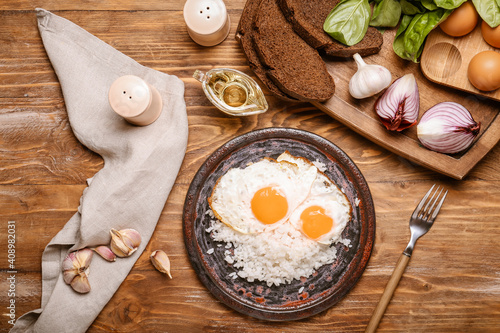 Plate with tasty eggs and rice on wooden background
