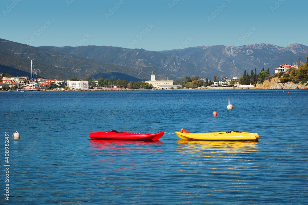 Obraz premium Red in yellow boats in a bay of picturesque Greek island called Poros in a sunny summer day.