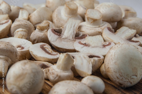 Fresh whole and sliced champignons on a dark board close-up. Selective focus