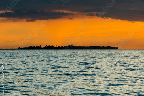 Dramatic orange tinged Sunset in the Bohol Strait. Silhoutte of Bugatusan Island, a small inhabited islet off the town of Inabanga. photo